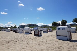 A row of numbered beach huts on a sandy beach with a clear sky. - to the view of the sun (Kröpelin, OT Wichmannsdorf)