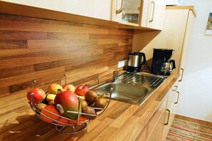 Eine Küche mit Holztresen, Obstkorb, Kaffeemaschine und Spüle aus Edelstahl.
