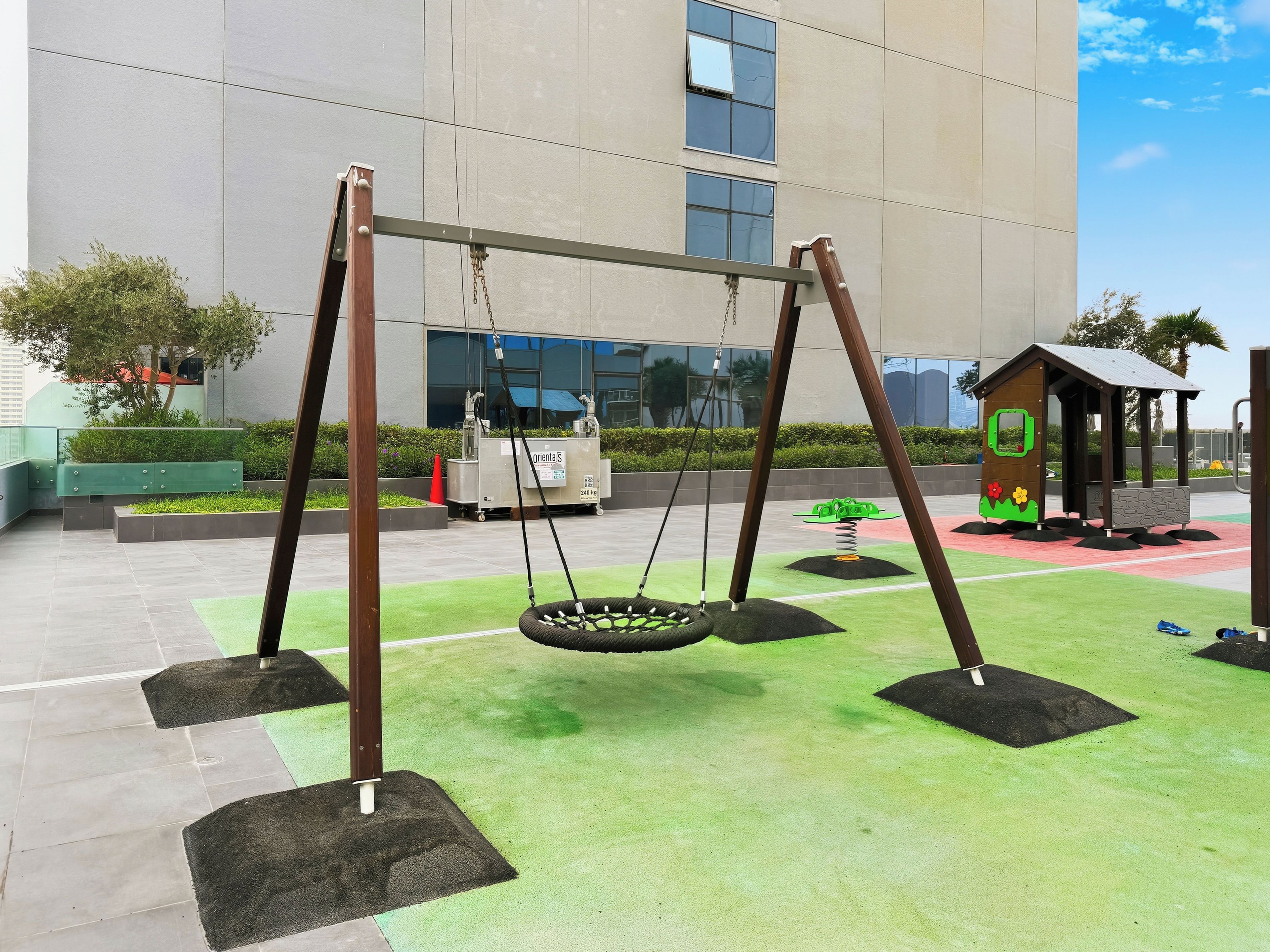 A playground with swings and a small playhouse.