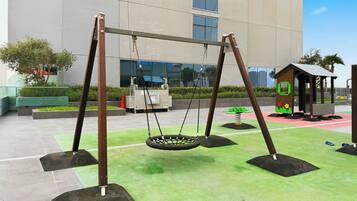 A playground with swings and a small playhouse.