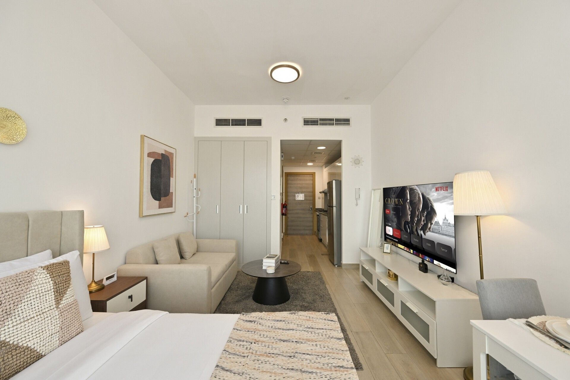 Une chambre d’hôtel comprenant un lit, un canapé, une télévision, une table basse et un meuble pour la télévision.