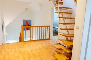 A wooden staircase with a railing, leading to an upper floor. - House by the paddock (Born\/ DarßMit)