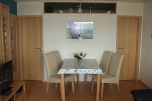 A dining area with a table, chairs, a television, and a window with a view. - Schneider Heiligenhafen Baltic Sea (Heiligenhafen)