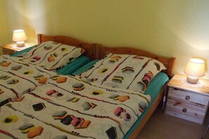 Ein Bett mit gemusterten Betttextilien, zwei Nachttische mit Lampen und ein hölzernes Kopfteil.