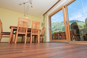 Ein Essbereich mit Holzmöbeln und einer großen Schiebeglasdoor, die zu einem schönen Ausblick ins Freie führt.