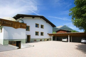 A two-story building with a white facade, a wooden balcony, and a mountain backdrop. - Thaneller Guesthouse Müller (Bichlbach)