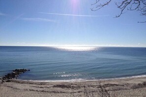 Ein Strand mit ruhigem Wasser, blauem Himmel und felsiger Küste.