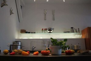 Eine Küche mit Spüle, Geschirr und verschiedenen Früchten und Gemüsesorten auf der Arbeitsfläche.