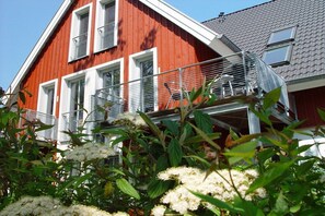 Ein rotes Gebäude mit weißer Fassade, einem Balkon und einem grauen Dach.