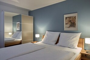 Ein Hotelzimmer mit Bett, Nachttischen, einem Spiegel und einem Bild an der Wand.