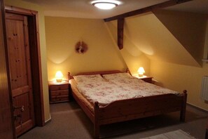 Ein Schlafzimmer mit einem hölzernen Bett, zwei Nachttischlampen, einer Wandleuchte und einer Tür.