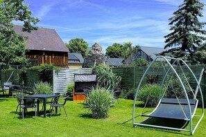 Ein Garten mit Schaukel, Holzlattenzaun und einem Haus mit geneigtem Dach.