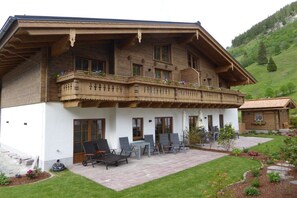 A two-story chalet with a balcony, outdoor seating, and a garden. - Hochalmbahnen Chalet (Rauris)