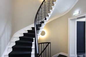A staircase with black railings and white steps, leading to a door with a light fixture above it. - Central Edinburgh Studio w/City Views & Workspace (Edinburgh)