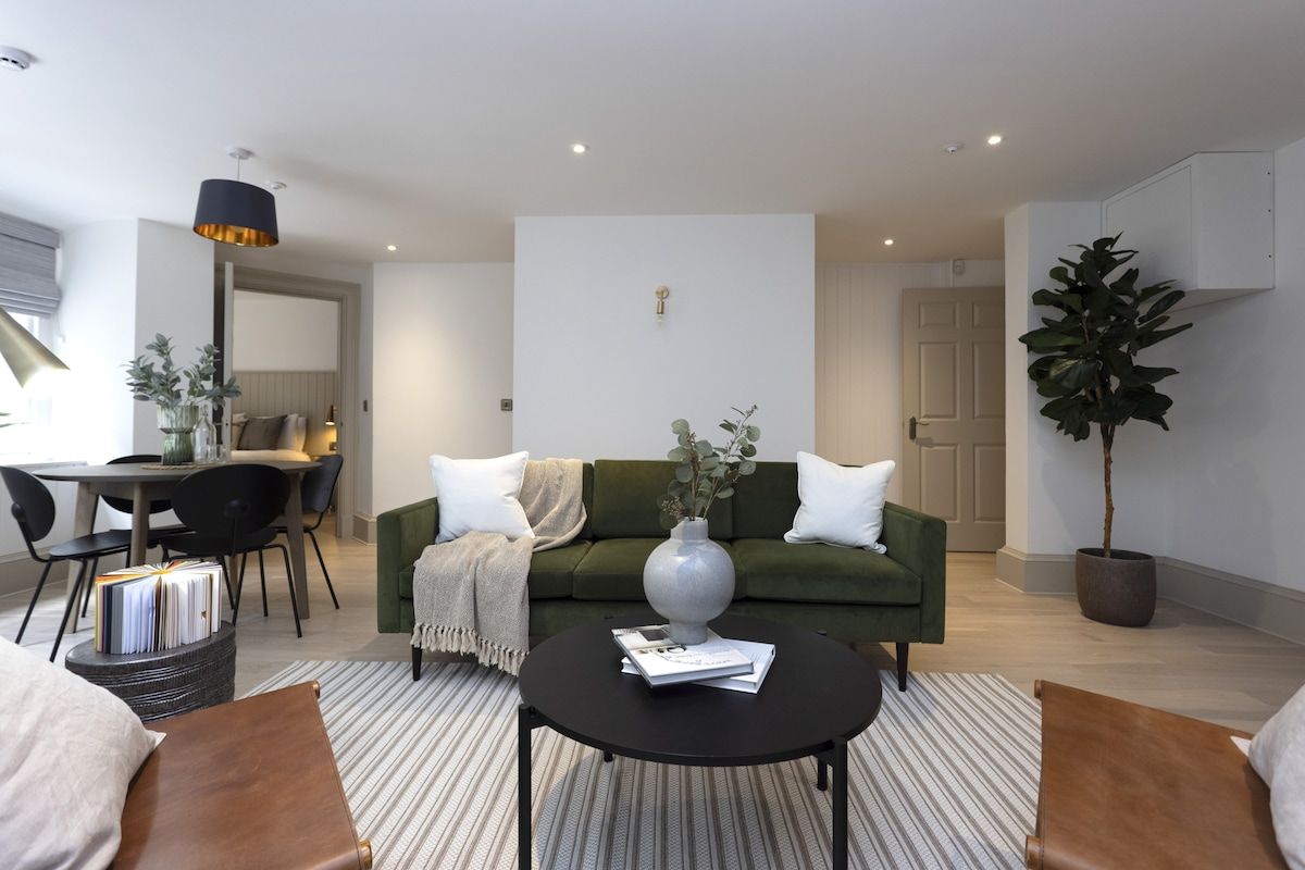 Un salon moderne avec un canapé vert, une table basse et un coin repas comprenant une table et des chaises.