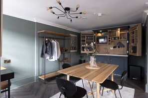A modern kitchen with wooden cabinets, a dining table with chairs, and a pendant light fixture. - Elegant Georgian Studio By Princes St with WiFi (Edinburgh)