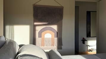 A bedroom with a bed, a wall-mounted tapestry, and a door leading to another room.