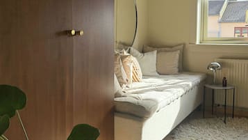 A bedroom with a bed, a potted plant, a radiator, and a window.