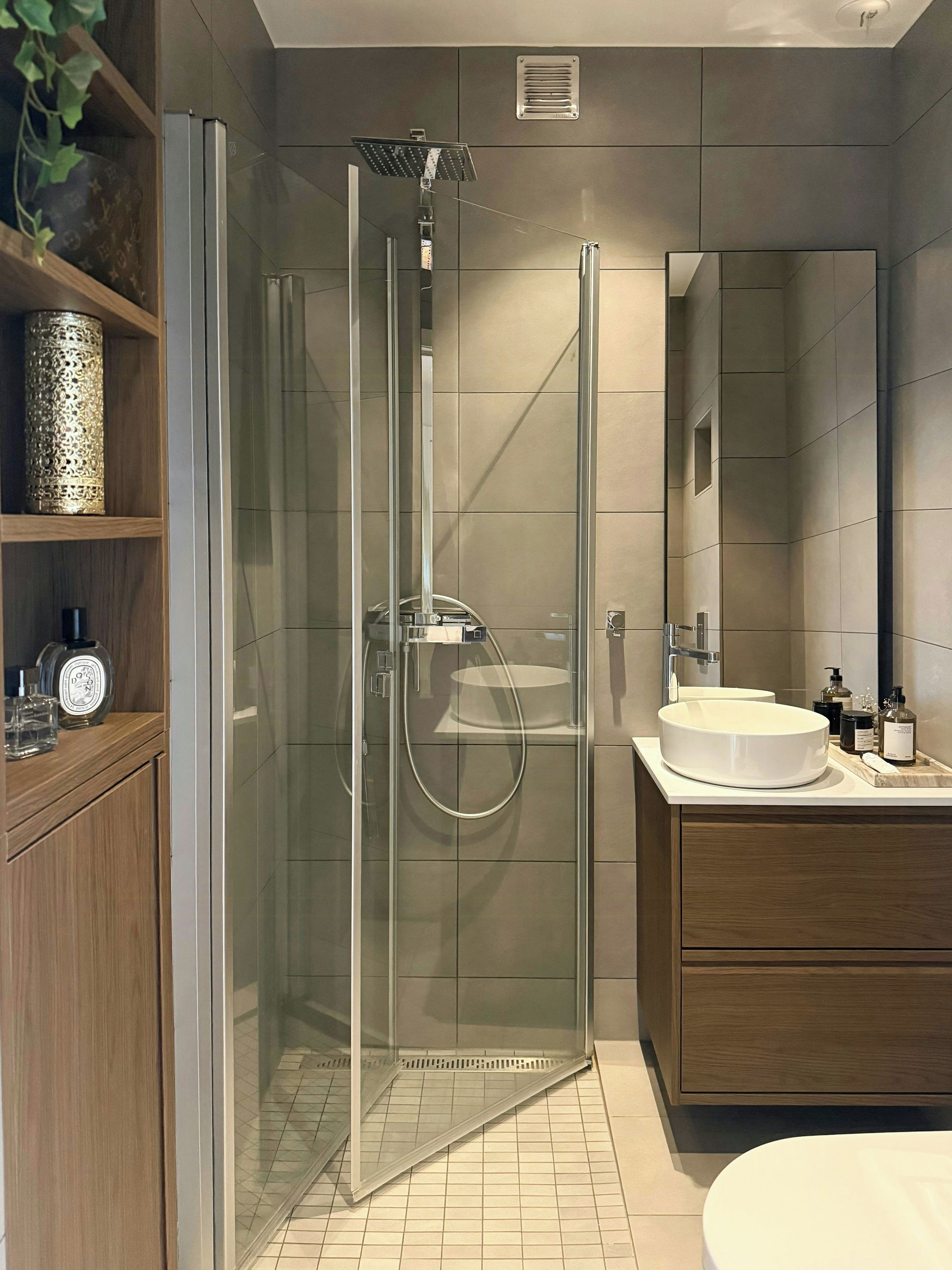 A modern bathroom with a glass-enclosed shower, a wooden vanity, and a round sink.