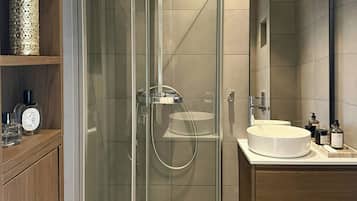 A modern bathroom with a glass-enclosed shower, a wooden vanity, and a round sink.