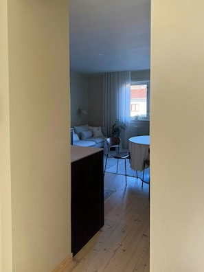 Un pasillo estrecho que conduce a una sala de estar con un sofá, una mesita y una silla.