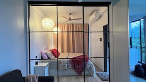 Une pièce dotée d’une porte coulissante, d’un lit avec une literie à motifs floraux, d’un ventilateur de plafond et d’un appareil de climatisation.