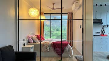 Un dormitorio con cama, mesita de noche y vistas a la vegetación a través de una ventana.