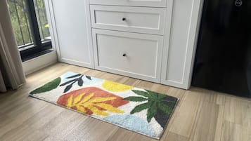 Una cocina con armarios blancos, un lavavajillas negro y un tapete colorido en el suelo.
