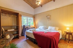 Ein Schlafzimmer mit einem Bett, einem Holzschrank, einem Schreibtisch und einem Fenster.