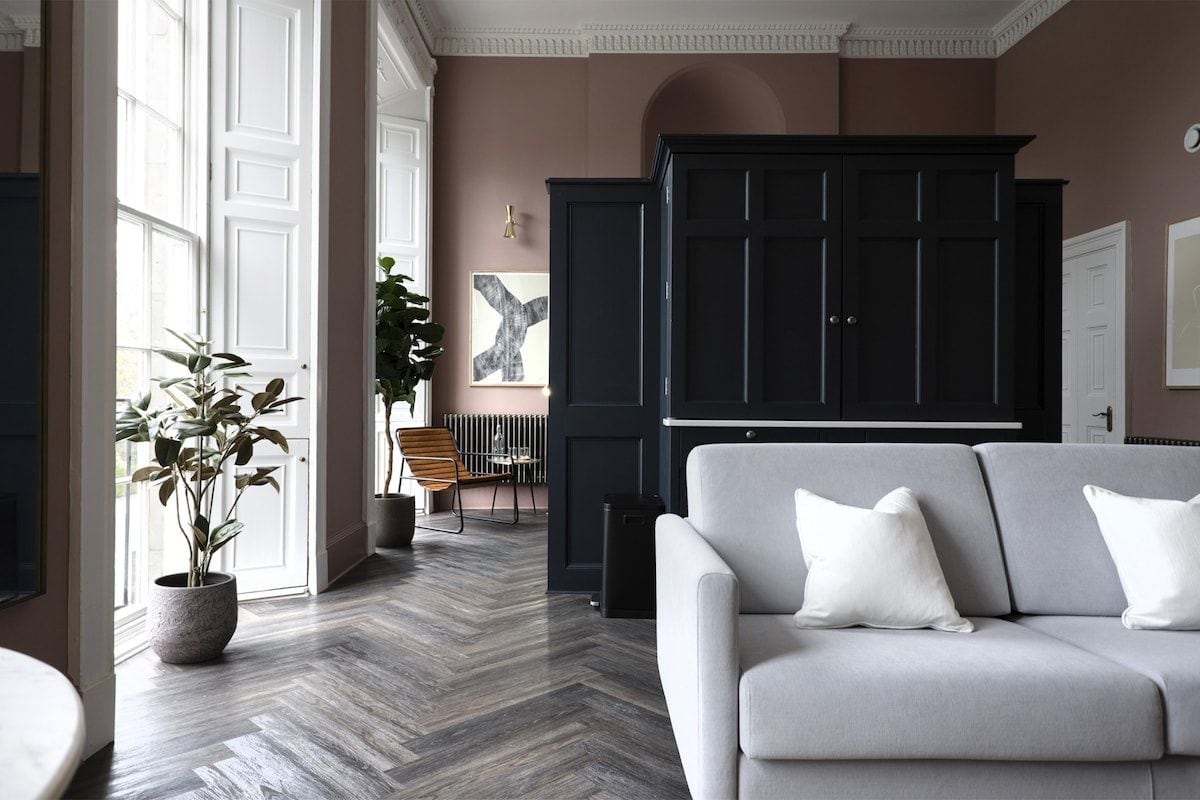 Un salon avec un canapé, une plante en pot et un meuble sombre.