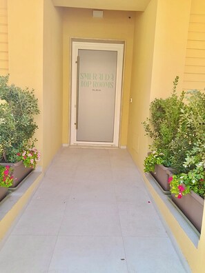 Corredor que leva a uma porta com uma placa que diz 'SMIRALDA TOP ROOMS'.
