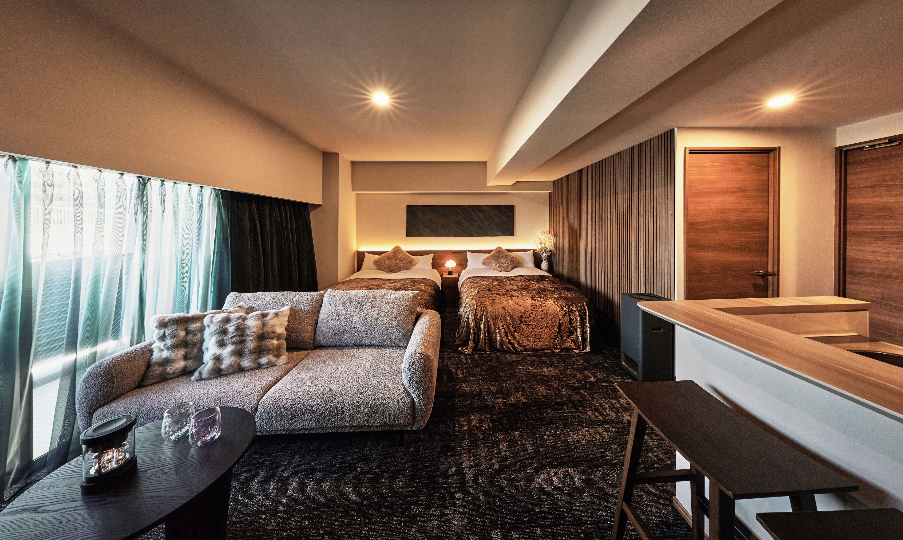 Et moderne hotelværelse med sofa, to senge, et spisebord og et badeværelse.