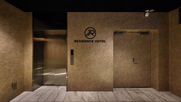 Un ascensore con un cartello che riporta 'RESIDENCE HOTEL' e un pannello di controllo con un pulsante.