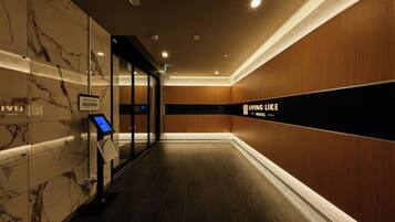 A hotel corridor with marble walls, a digital kiosk, and a sign reading 'LIVING LIKE HOTEL'.
