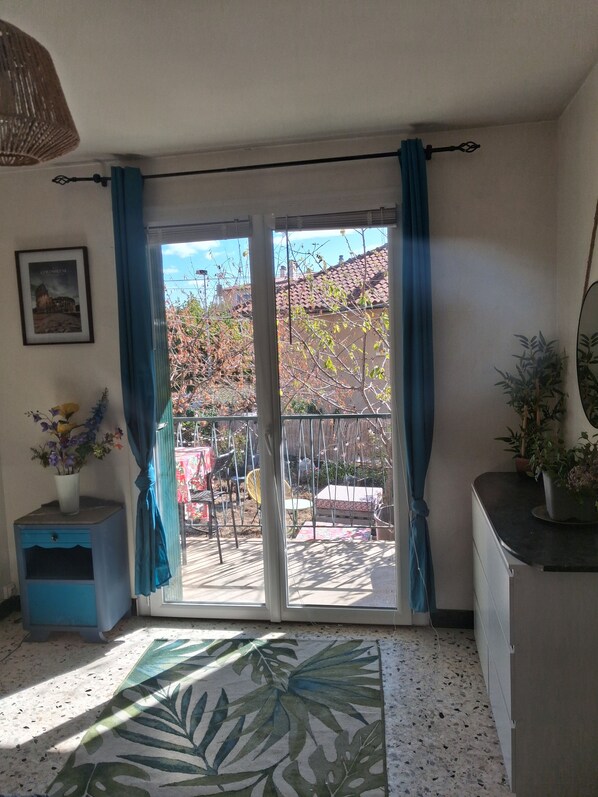 A room with a sliding glass door leading to an outdoor area with a patio and a view of a building.