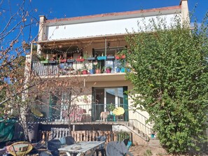A two-story building with balconies, outdoor seating, and potted plants.