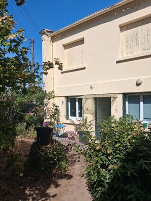 A two-story building with a garden entrance, a pathway, and outdoor furniture. - Vrbo Property (Millau)
