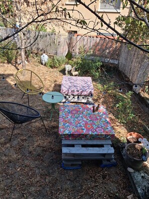 A backyard with a wooden table and chairs, a small round table, and a potted plant. - Vrbo Property (Millau)