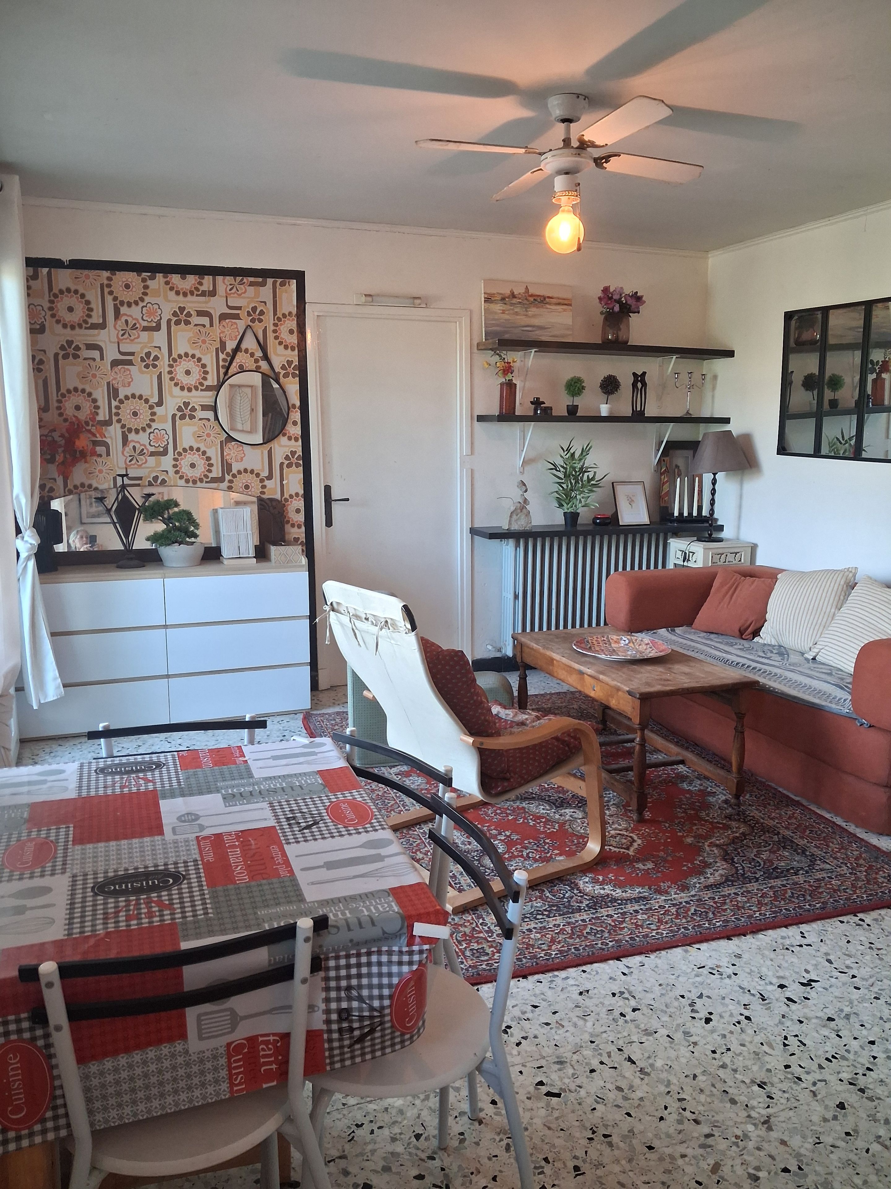 Un salon chaleureux avec une table à manger, un canapé et un ventilateur de plafond.