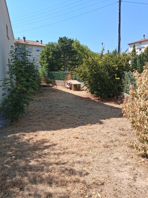 A residential area with a grassy yard, a small shed, and a house with a tiled roof.