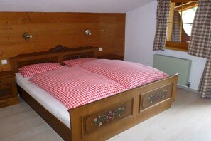A wooden bed with a checkered bedspread in a room with a wooden headboard and a radiator. - Holiday home in Auffach with swimming pool (Auffach)