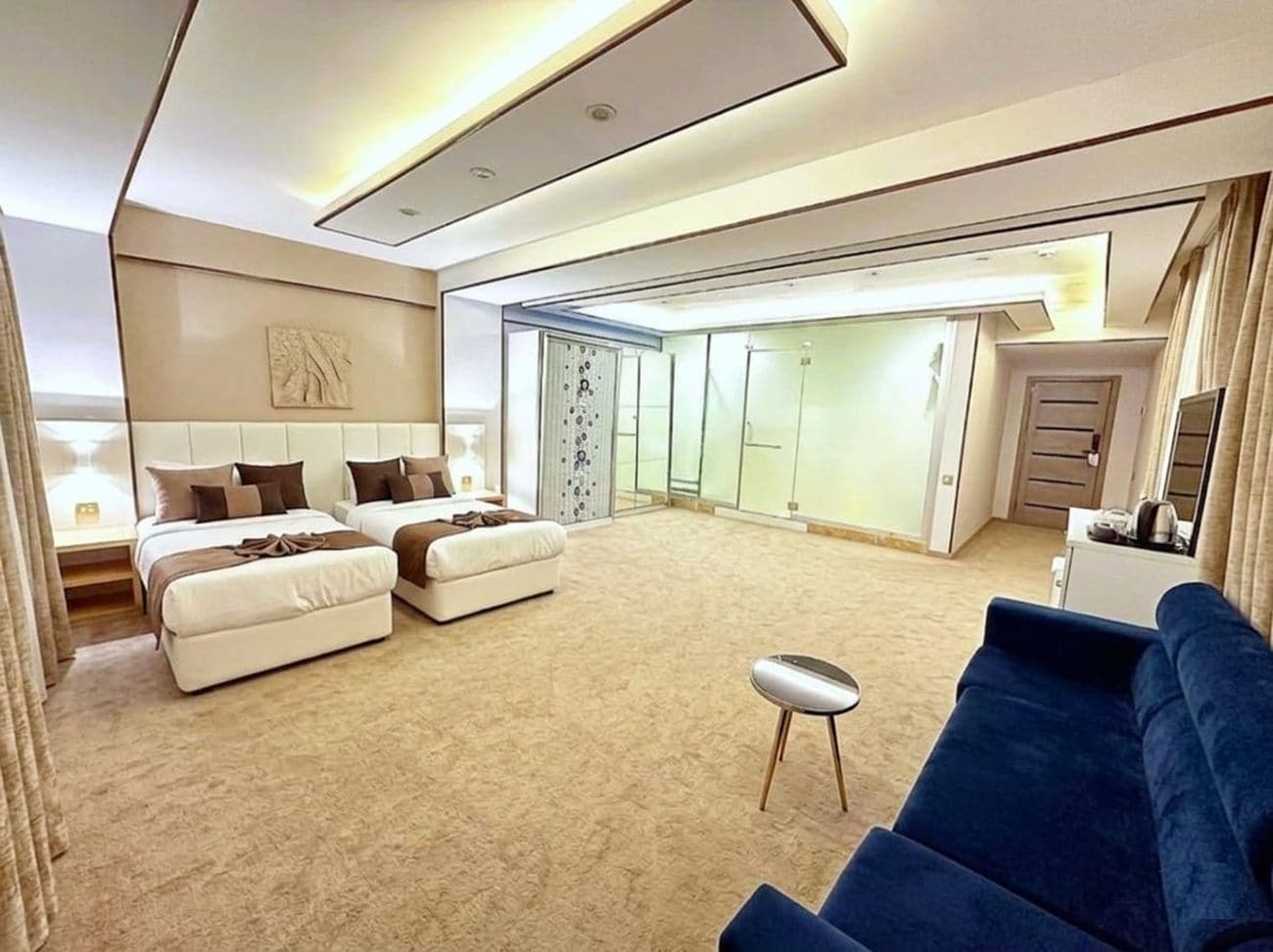 Een moderne hotelkamer met een groot bed, een bank, een klein tafeltje en een inloopkast.