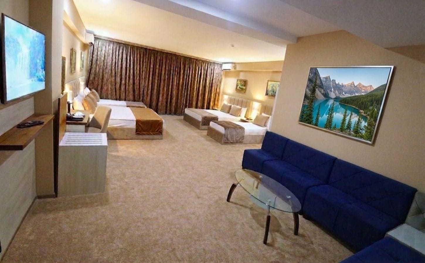A modern living room with a sofa, a glass coffee table, and a TV mounted on the wall.