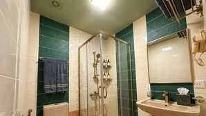 Ett badrum med en dusch som är avskärmad med glasväggar, en toalett och ett handfat med en spegel ovanför.