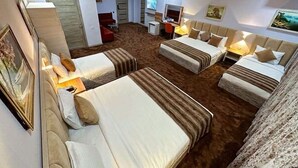 Ett hotellrum med två sängar, ett skrivbord, en TV och en dörr som leder till ett annat rum.