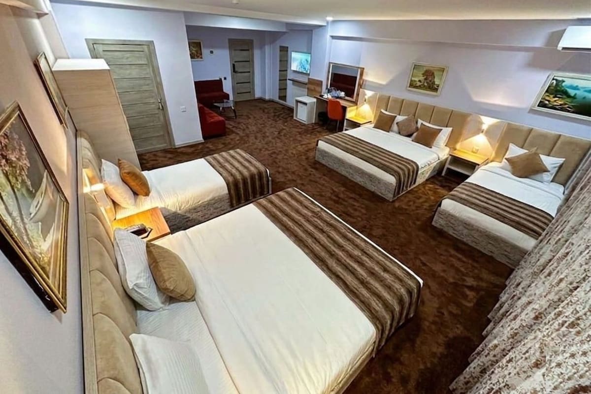Habitación de hotel con dos camas, un escritorio, un televisor y una puerta que da a otra habitación.