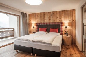 Une chambre avec un mur lambrissé en bois, un lit avec une tête de lit noire, deux lampes de chevet et une petite table d’appoint en bois sur laquelle est posé un vase.