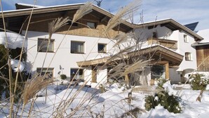 Un edificio de varios pisos con techo inclinado, balcones de madera y suelo cubierto de nieve.