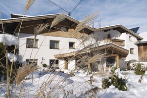 Un immeuble à plusieurs étages, doté d’un toit en pente, de balcons en bois et d’un sol recouvert de neige.