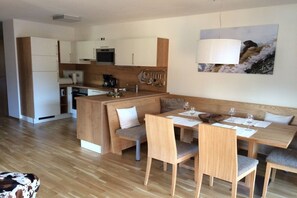 A modern kitchen with white cabinets, a wooden island, and a dining area with a bench and chairs. - Alpine Chalet Hohe Tauern (Matrei i. Osttirol)